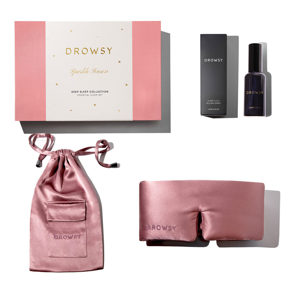 A pink Damask Rose - Deep Sleep Collection gift box with a luxury silk sleep mask, matching pink silk pouch, and a dark bottle of deep sleep pillow spray arranged neatly together.