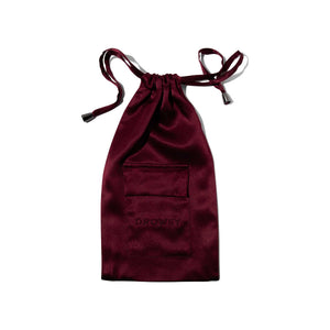 The La Vie En Rouge Silk Carry Pouch is a burgundy satin pouch with a small front pocket, subtly embossed with DROWSY—perfect for storing your silk sleep mask, shown against a white background.