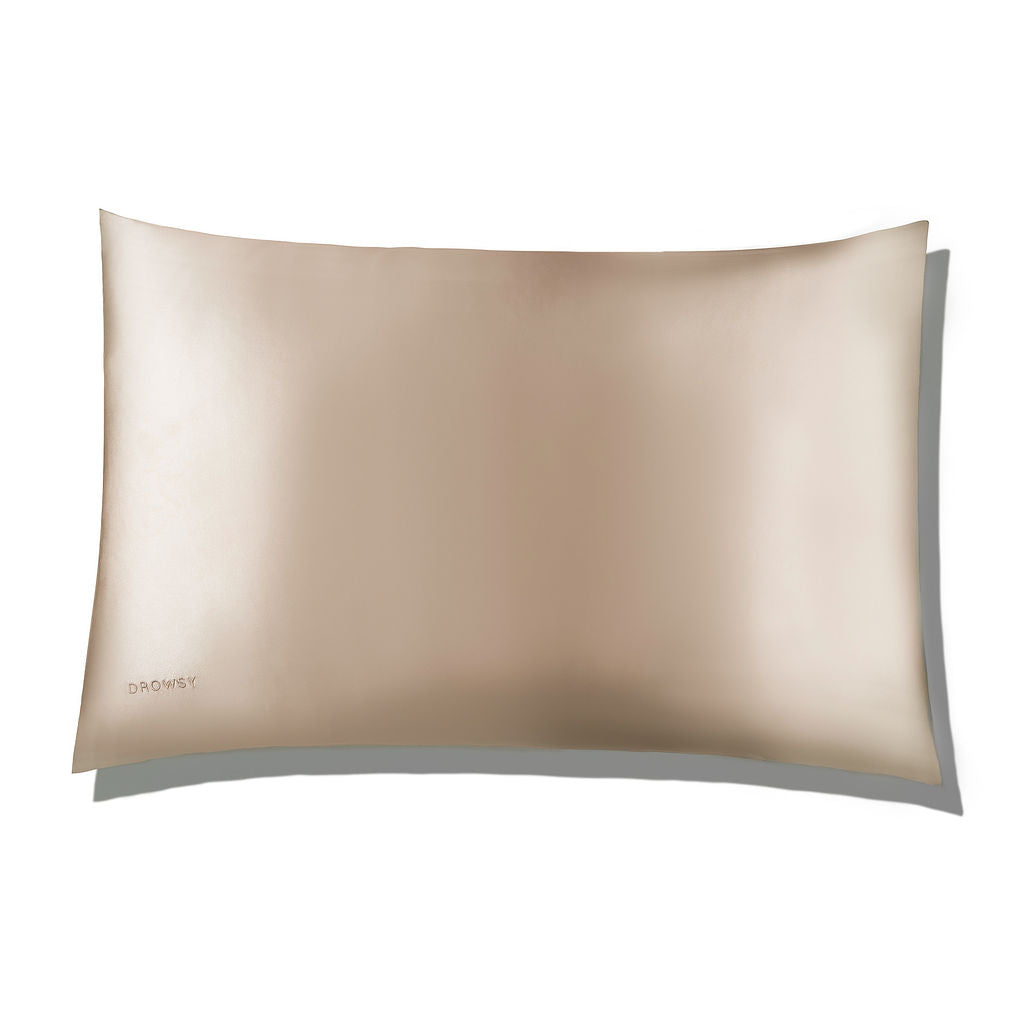 A smooth, light gold satin pillowcase with a subtle sheen, shown against a white background. The brand name DROWSY is lightly embossed in the lower left corner.