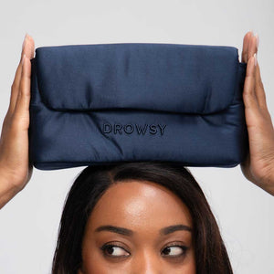 A person holds the Drowsy Silk Necessaire in Midnight Blue above their head, with only the top of their face and hands visible—a luxurious Drowsy accessory to elevate any beauty routine.