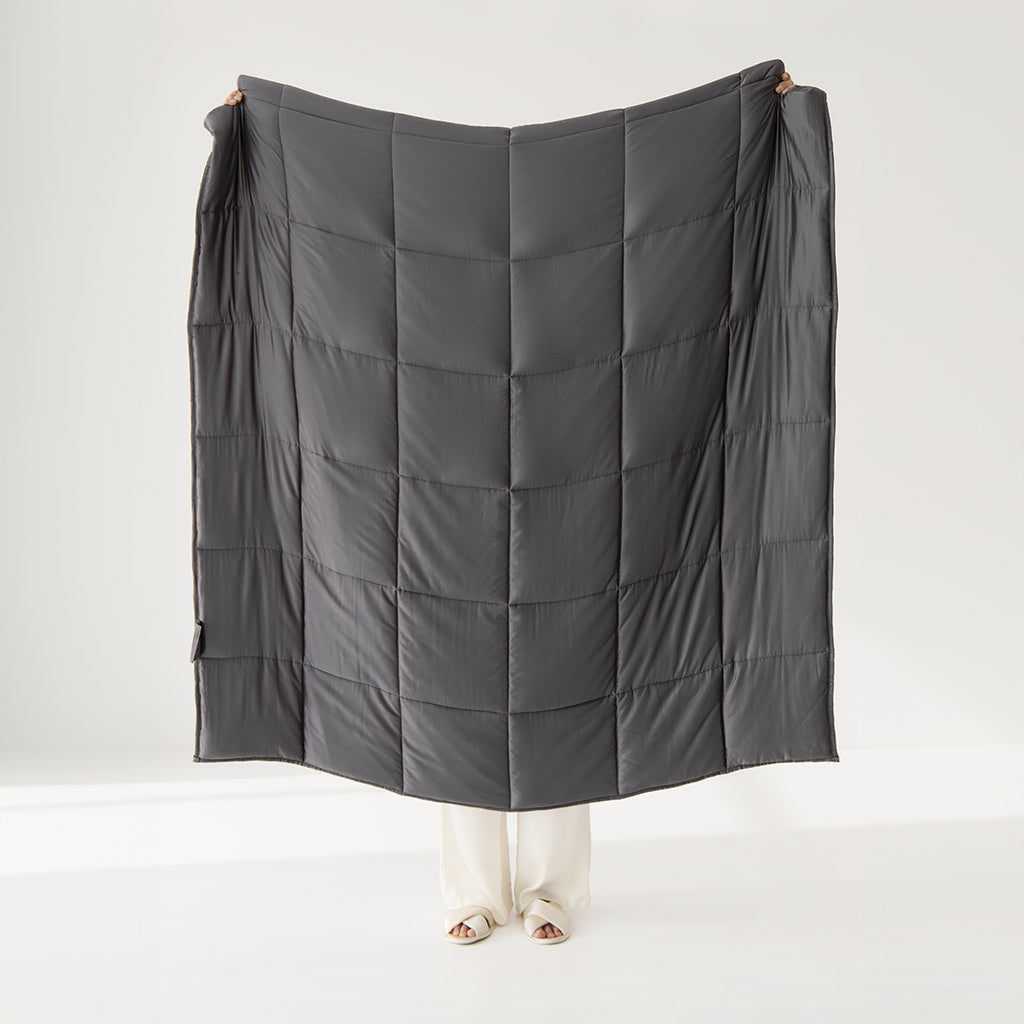 A person holding the Moonlight Shadow Silk Weighted Blanket, perfect for deep relaxation.