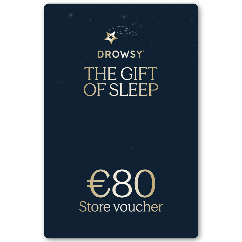 A dark blue Sleep Gift Card with gold text reading "Drowsy The Gift of Sleep" and “€80 online store voucher” below, surrounded by small star designs at the top.