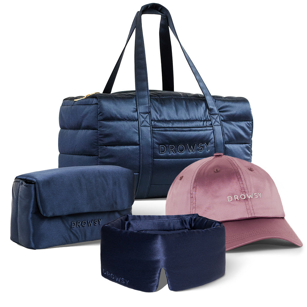The Perfect Scape Bundle - Midnight Blue by drowsysleepco includes a navy duffel bag, toiletry bag, silk sleep mask, and mauve pink cap—each embroidered with “DROWSY.”.