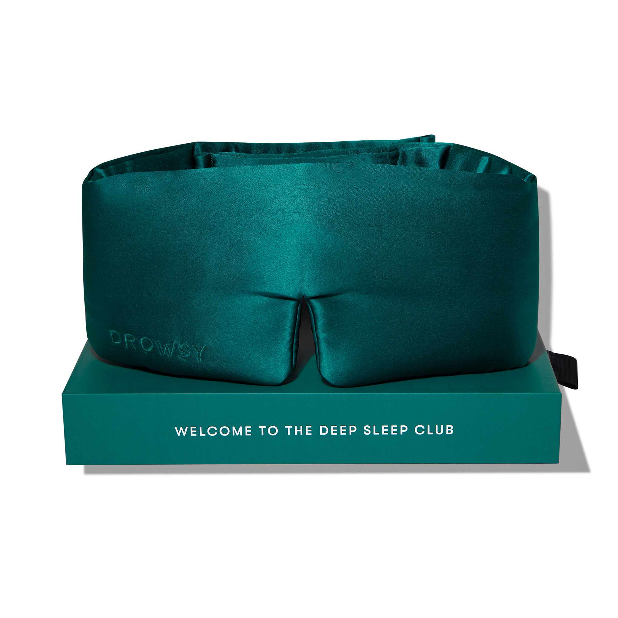 A Green Sapphire silk eye mask rests on a matching box labeled WELCOME TO THE DEEP SLEEP CLUB, with DROWSY subtly embossed on the blackout mask—ideal for beauty sleep.