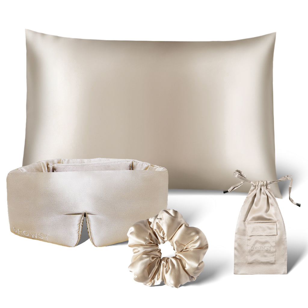 The Sensual Sleep Bundle - Dusty Gold by drowsysleepco features a beige silk pillowcase, sleep mask, scrunchie, and a matching drawstring pouch, all elegantly arranged on a white background.