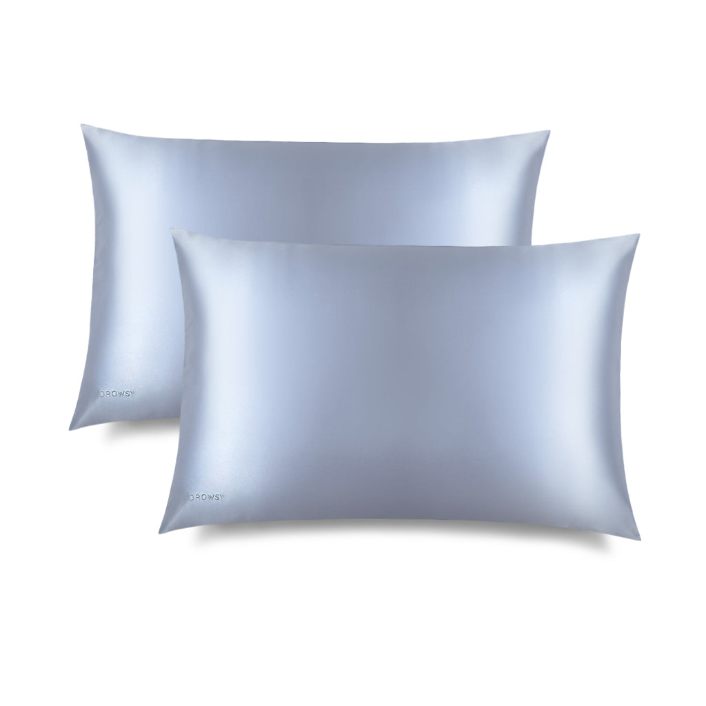 Two Blue Belle Silk Pillowcases, in smooth light blue silk with a subtle sheen, lies flat on a white background. DROWSY is printed on the bottom left—ideal for hair protection and beauty routines.