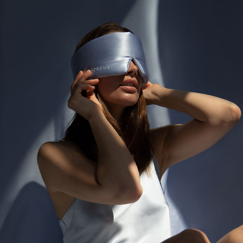 Model blocking sunlight from her eyes with a blue silk sleep mask