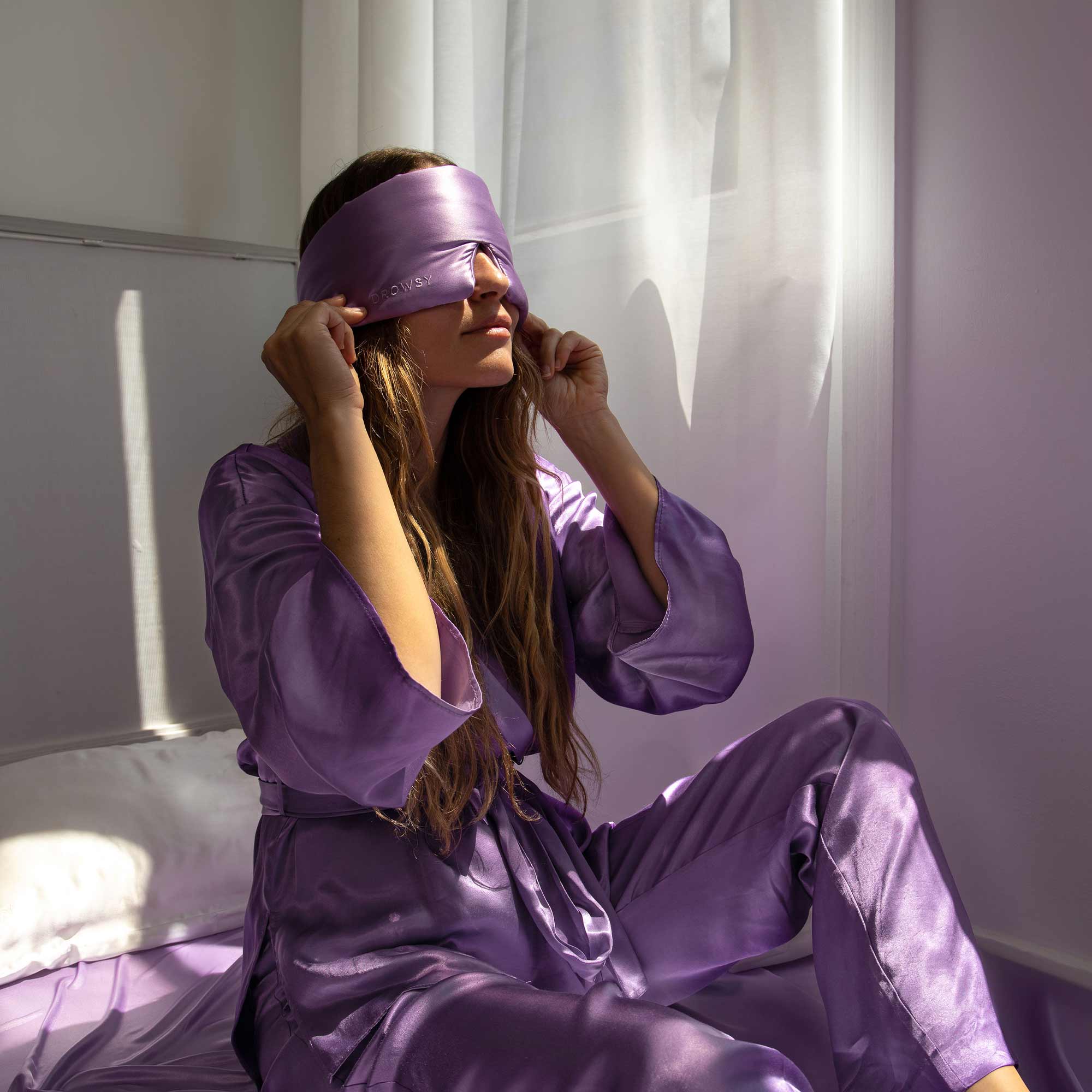 Model with Lavender coloured Drowsy sleep mask covering eyes with a white backdrop