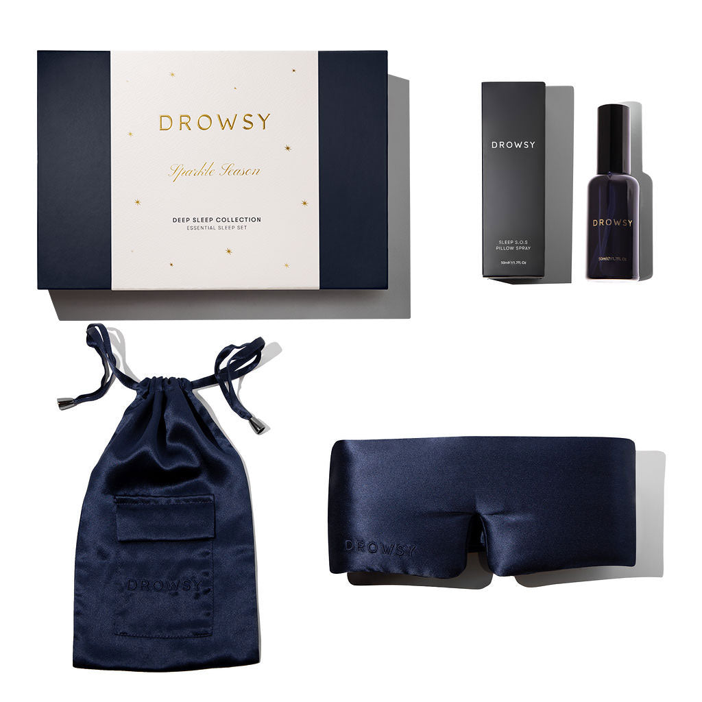 Introducing the Midnight Blue - Deep Sleep Collection: a luxury gift set with Drowsy's silk sleep mask, matching pouch, deep sleep oil in box, all presented in a navy and gold "Drowsy Sparkle Seven Deep Sleep Collection" gift box.