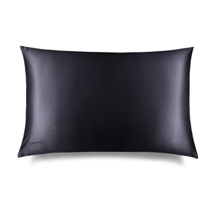 The Moonlight Shadow Silk Pillowcase, rectangular and smooth in black silk with DROWSY embroidered in the lower left corner, is shown on a white background with a subtle right shadow—ideal for skincare and hair protection.