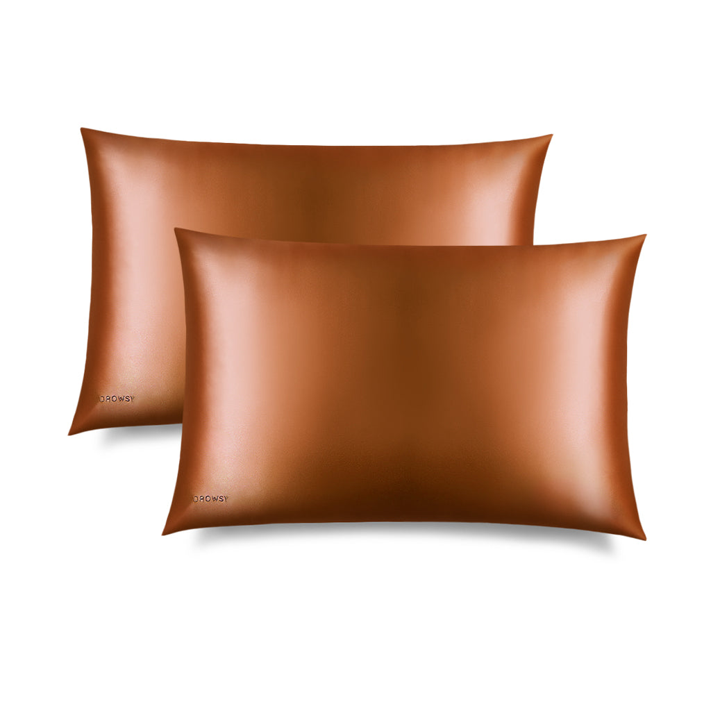 Two Pumpkin Spice Silk Pillowcases, in a shiny bronze hue, is displayed on a white background with a “DROWSY” logo in the corner—an essential for skincare and beauty, perfect for protecting your hair.