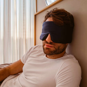 A man wearing the drowsysleepco 2-Pack Sleep Masks in Paris Love Story and Midnight Blue.