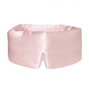 The Sunset Pink eye mask is a light pink, padded silk mask with DROWSY embroidered on the side and a nose notch—ideal for beauty sleep and reducing dark circles.
