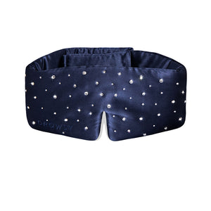The Drowsy Silk Eye Mask Crystals by Swarovski® is a navy blue blackout mask adorned with Swarovski crystals, featuring “DROWSY” embossed on the left side and a notched bottom center for extra comfort.