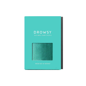 The turquoise Breakfast at Drowsy Carry Pouch box has a clear window displaying a teal mulberry silk pouch, ideal for your sleep mask, with Breakfast at Drowsy printed at the bottom.