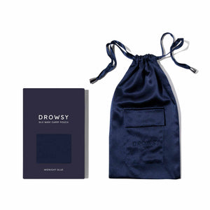 The Midnight Blue Silk Carry Pouch, made from mulberry silk with a small front pocket, sits next to its matching box labeled Drowsy Silk Mask Carry Pouch Midnight Blue—a stylish way to store your sleep mask.