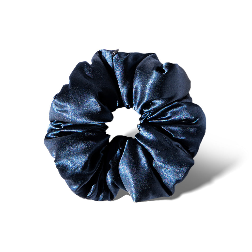 The Midnight Blue - Padded Scrunchie, featuring a shiny, deep blue hue, is shown oversized against a white background with a soft shadow cast to the right.