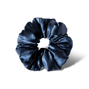 The Midnight Blue - Padded Scrunchie, featuring a shiny, deep blue hue, is shown oversized against a white background with a soft shadow cast to the right.