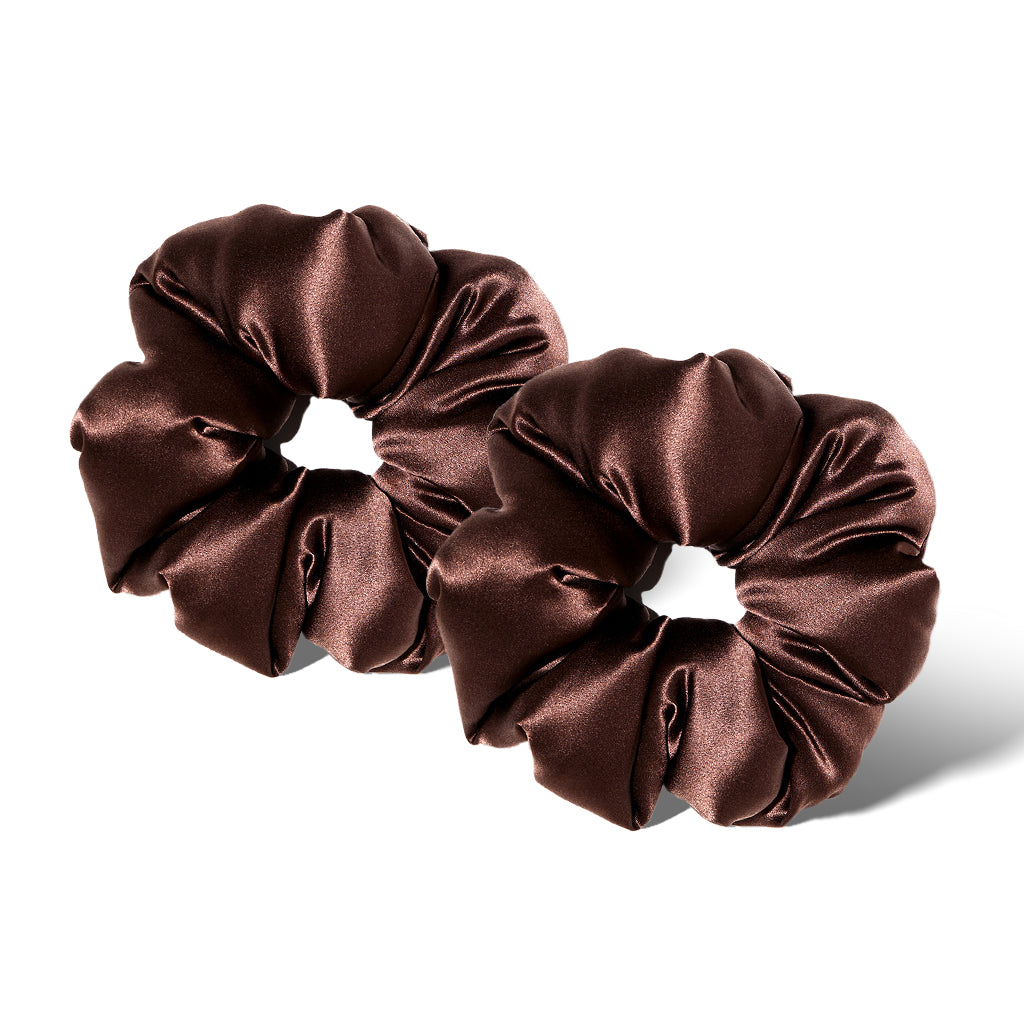 Two shiny, dark brown oversized Cocoa Glow - Padded Scrunchies rest side by side on a white background, casting soft shadows—perfect for adding style and caring for your hair’s health.