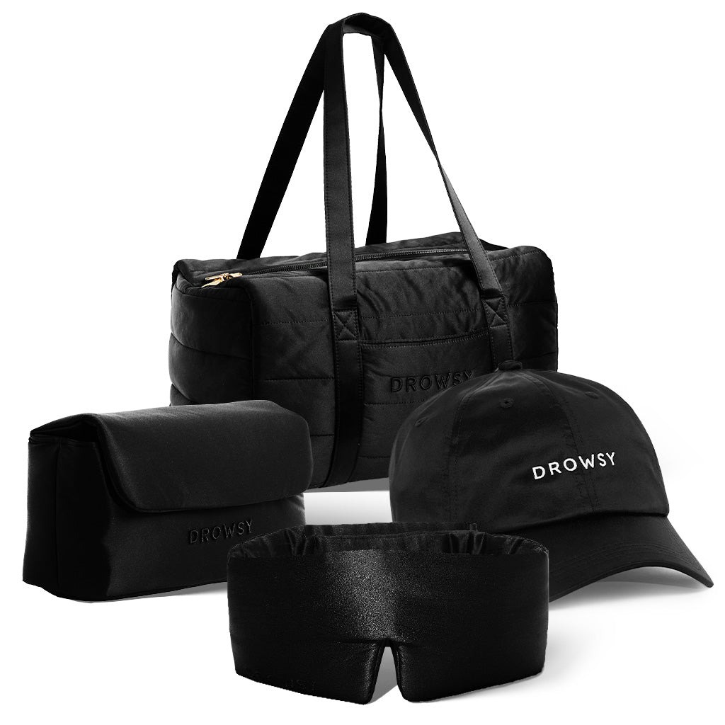 The drowsysleepco Perfect Scape Bundle - Black Jade, featuring a black duffel bag, matching toiletry bag, silk sleep mask, and embroidered cap, is arranged together against a white background.