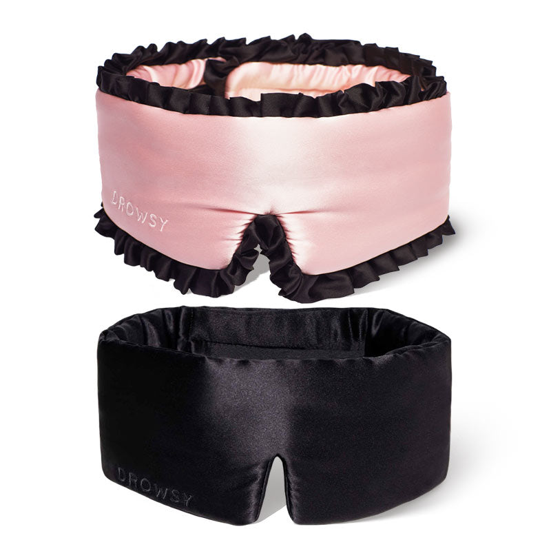 The 2-Pack Sleep Masks by drowsysleepco features one pink silk mask with black ruffled edges and one sleek black jade silk mask, both embossed with the DROWSY logo on the side.