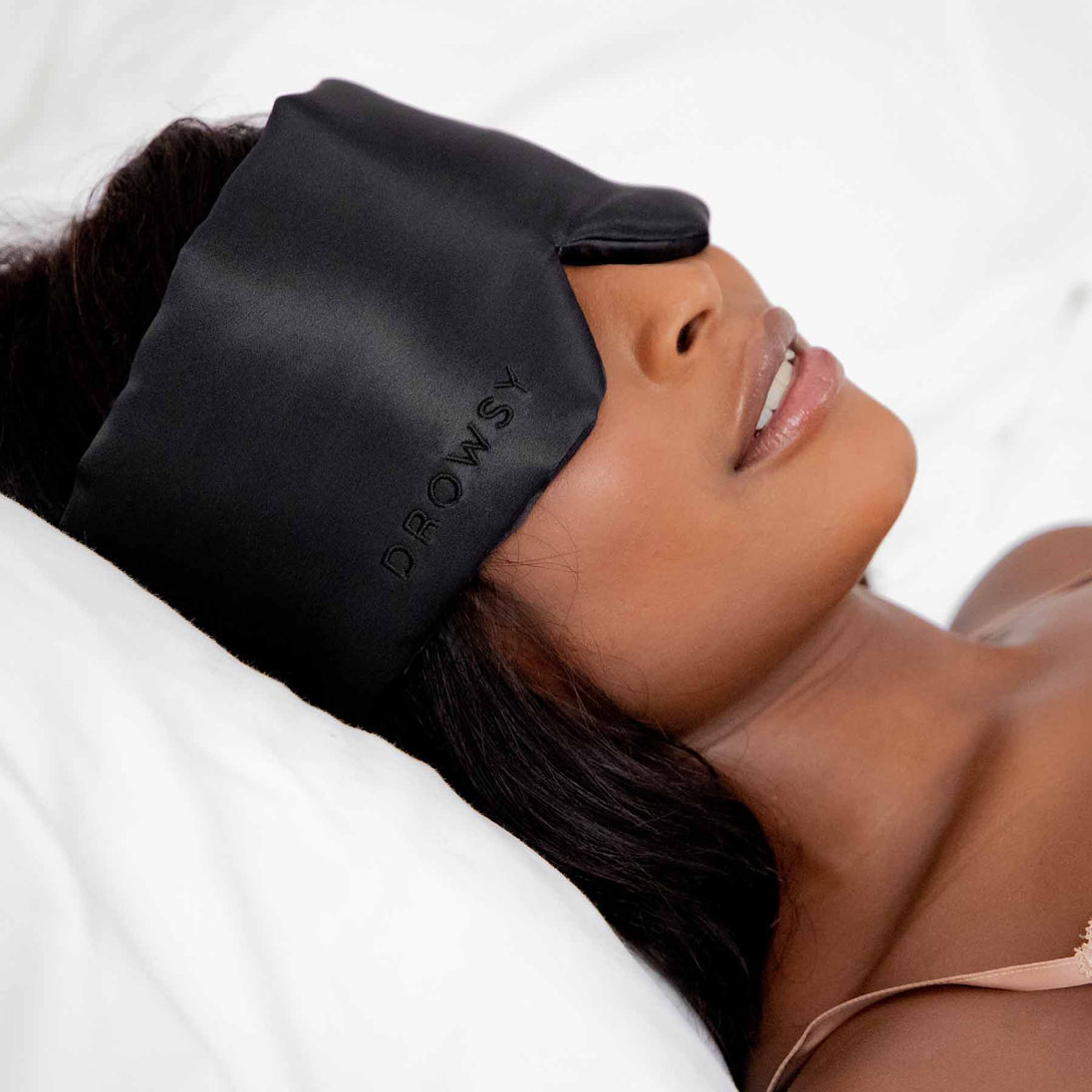 Model sleeping in bed with Black Jade Drowsy Sleep Co Silk sleep mask covering eyes