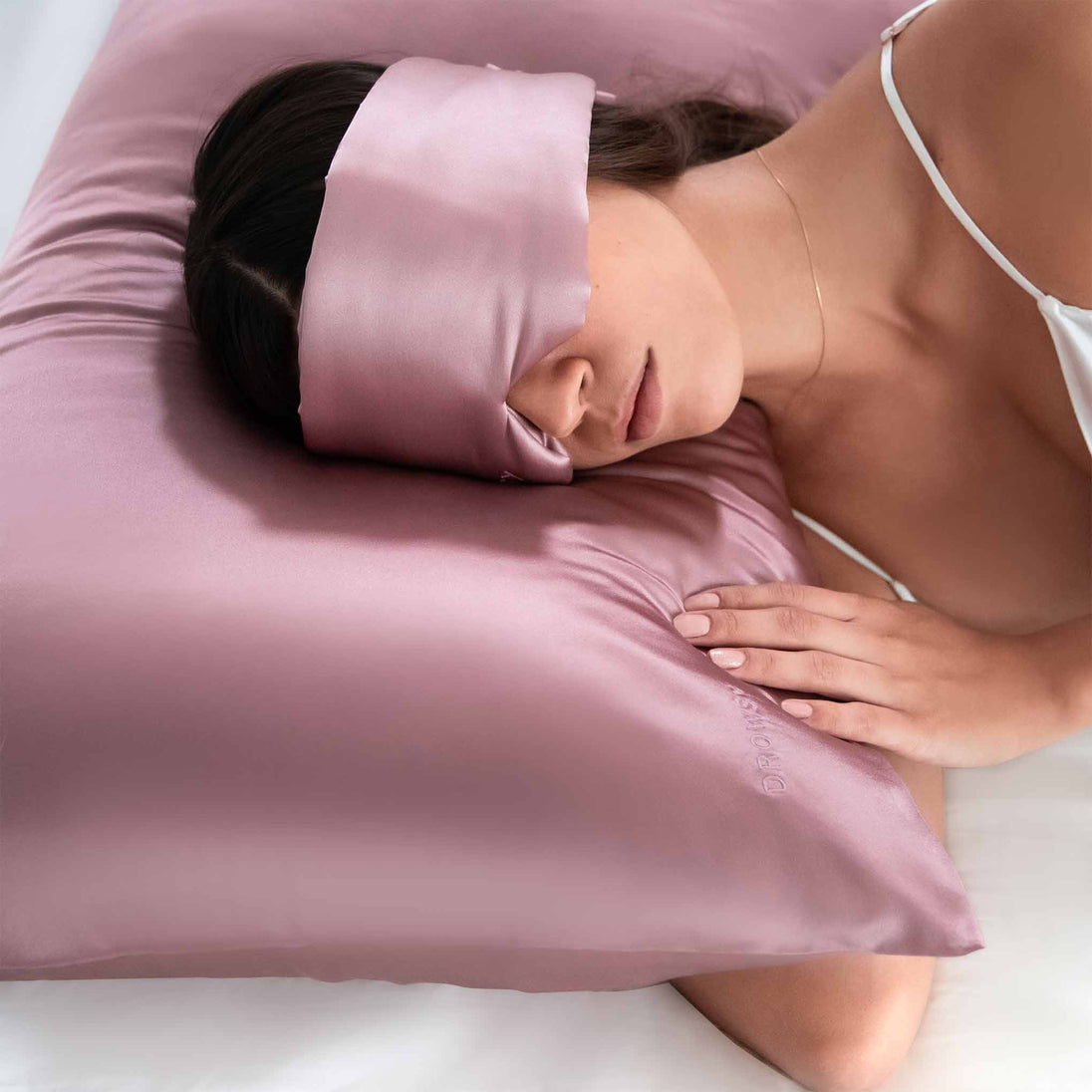 Girl sleeping on pink silk pillowcase with Drowsy Sleep Co silk mask covering her eyes