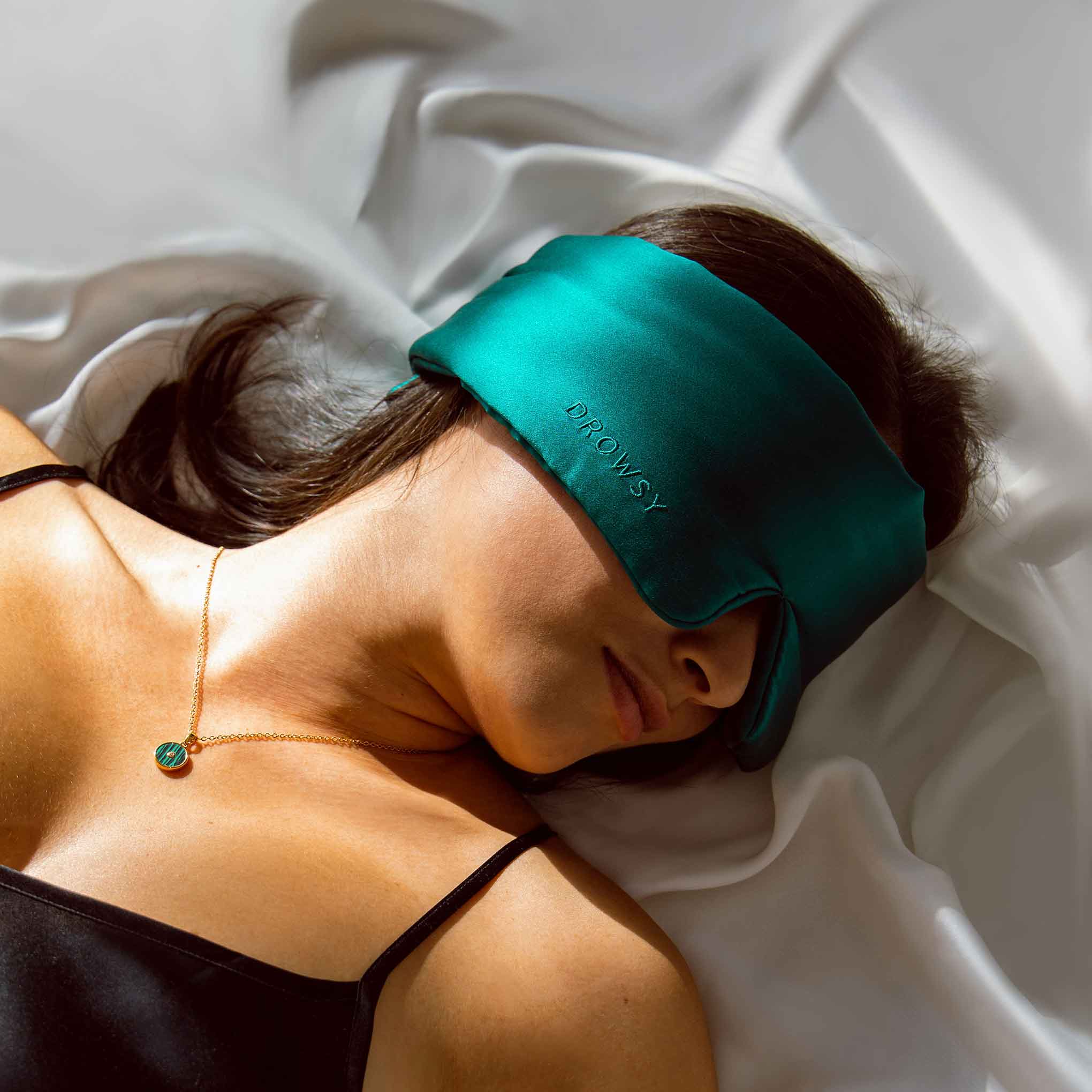 Girl sleeping on white silk with Drowsy Silk Sleep Mask covering eyes